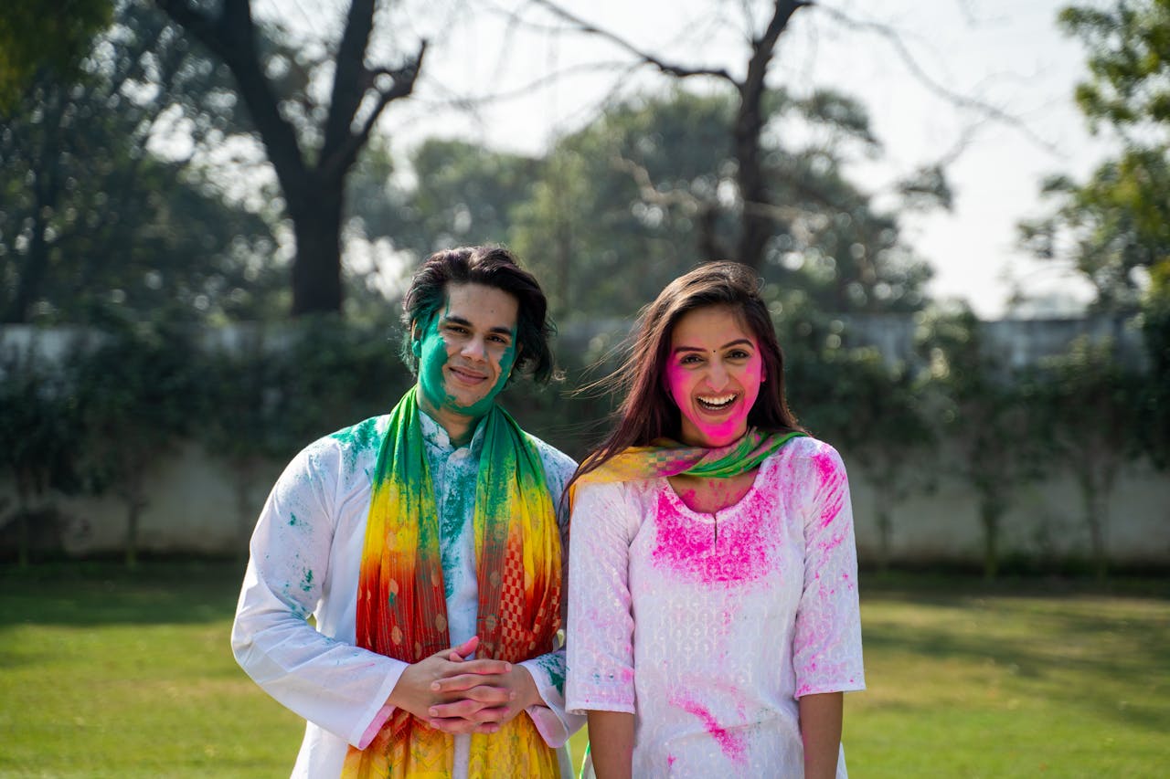 A Man and a Woman with Colorful Powder on their Faces Smiling at the Camera